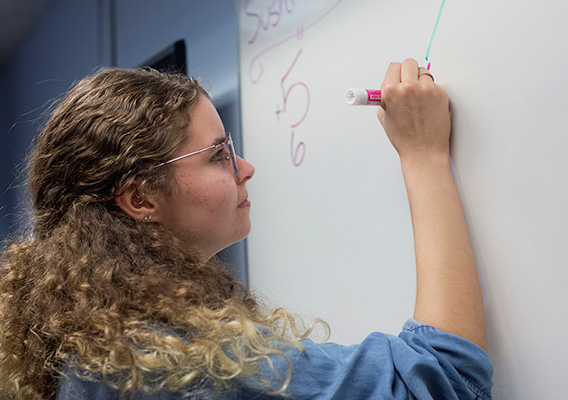Honors student completes a math equation on the whiteboard