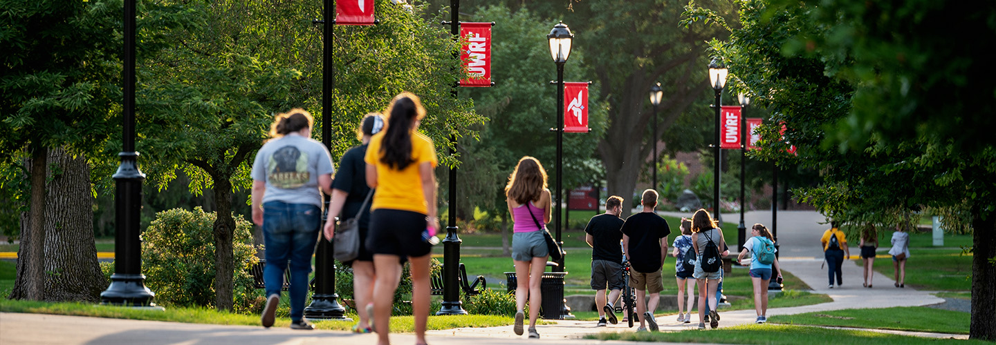 Several students walk down the sidewalk on the campus mall