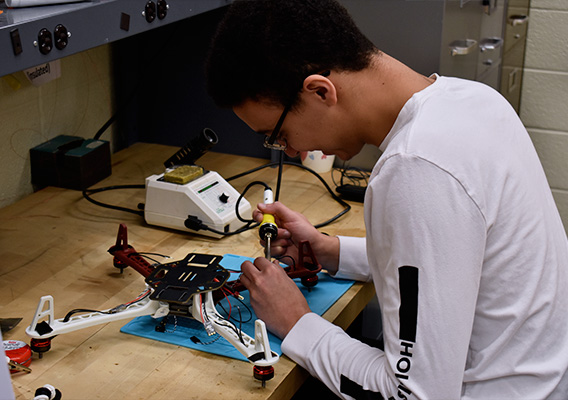 A student works on soldering the internal components of a drone during class