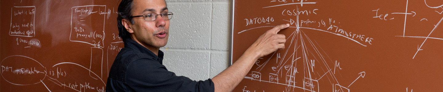 Physics professor points to a drawn diagram on a chalkboard