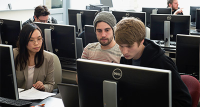 Three students looking at a computer screen in a Business Administration class