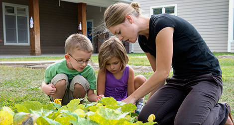 Student shows a garden to children at the CHILD Center on campus