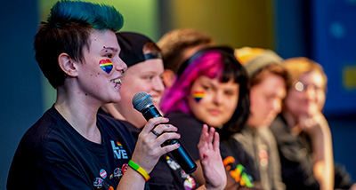 Group of students speak on stage during pride month