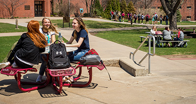Three students enjoy the weather outside on campus