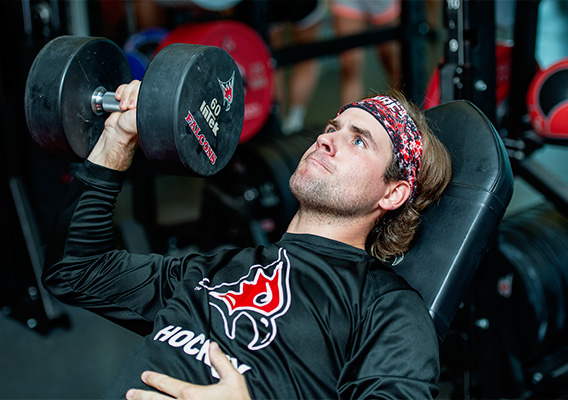 Strength and Conditioning Graduate student lifts weights in the campus gym
