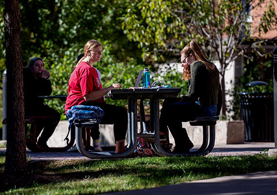 Group of students sit at a picnic table outside