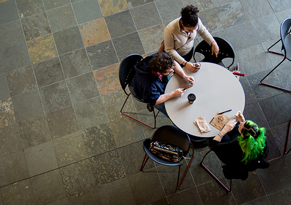 Three students sit at a table in the University Center