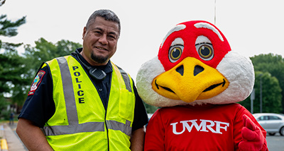 University Police officer stands next to Freddy Falcon on Move-In Day